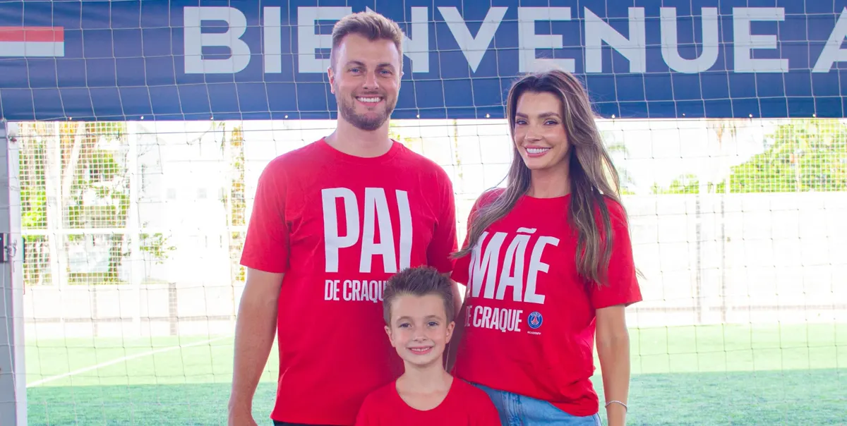 Família com camisetas vermelhas da PSG Academy escritas Pai de craque e Mãe de craque